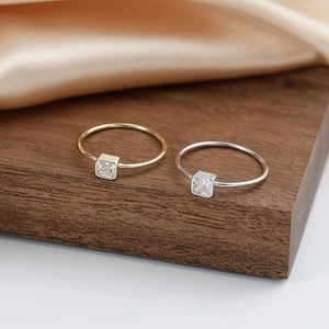 Minimalist S925 sterling silver rings with square zircon stones on a rustic wood base