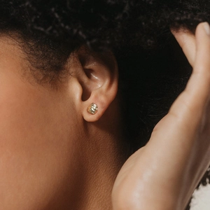 Gros plan de boucles d'oreilles dorées froissées et irrégulières sur un mannequin
