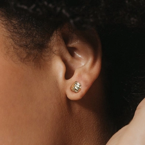 Boucles d'oreilles dorées minimalistes à texture irrégulière sur un modèle féminin