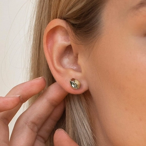 Close-up of a minimalist gold irregular droplet earring on a woman's earlobe