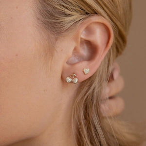 Macro shot of 925 silver cherry and heart stud earrings with cubic zirconia on ear