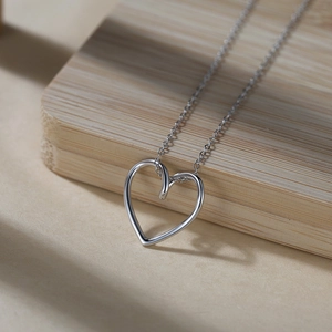 Vue macro du pendentif cœur minimaliste en argent S925 sur une fine chaîne à maillons