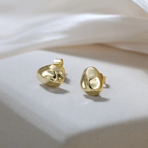 Detail of irregular pebble-shaped gold stud earrings with polished mirror finish surface