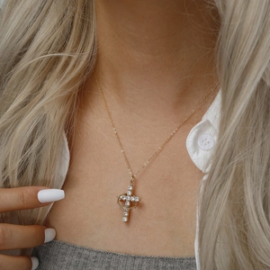Elegant gold crown cross necklace with sparkling cubic zirconia on a female model