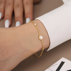 Detailed view of a gold-plated sterling silver bracelet with a pearl and zircon accents