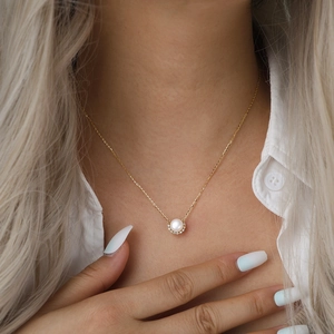 Elegant gold chain necklace with round pearl pendant and pavé rhinestones on model
