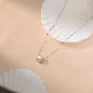 Elegant smile pearl necklace with silver halo pendant on a textured shell background