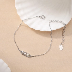 Elegant S925 sterling silver pod bracelet with three white pearls on a textured background