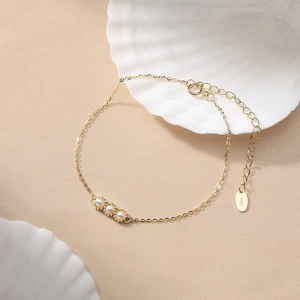Elegant gold S925 silver pea pod pearl bracelet with a white shell on beige background
