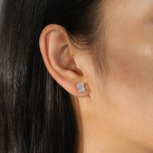 Detail shot of a rectangular princess cut zircon earring on a female model's ear