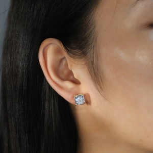 Close-up of a square princess cut zircon stud earring in a four-prong gold setting