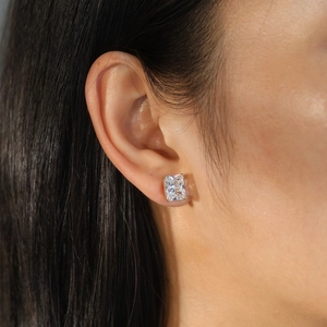 Detail of square radiant cut zircon stud earring in gold claw setting on model ear