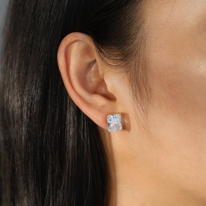 Macro shot of silver stud earring with emerald cut cubic zirconia on female earlobe
