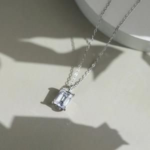 Macro shot of silver S925 necklace featuring an emerald-cut zircon pendant in four-prong setting