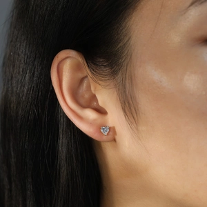 Gros plan d'une boucle d'oreille en argent S925 avec zircon en forme de cœur sur l'oreille