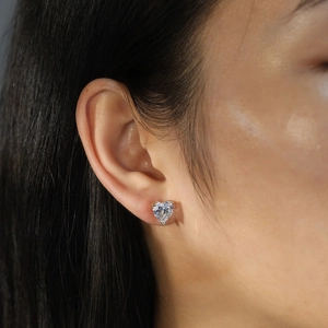 Gros plan d'une boucle d'oreille cœur en zircon et argent S925 à 3 griffes sur l'oreille