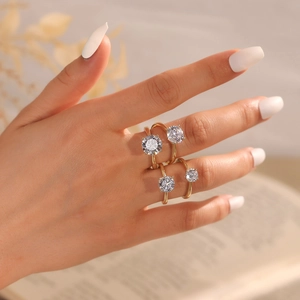 Close-up of a set of four thin gold rings with round clear stones worn on a hand