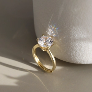 Macro shot of six-prong round cut sparkling solitaire ring with gold plated finish