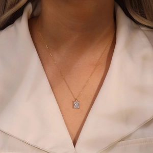 Detail of elegant gold necklace featuring a rectangular zircon pendant on a woman