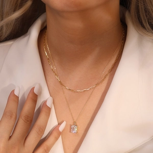 Detail of layered gold necklace featuring a rectangular cut zircon pendant on a model