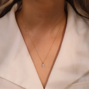 Gros plan d'un collier doré 14 carats avec pendentif en zircon en forme de poire