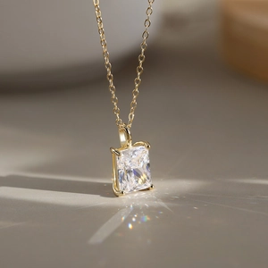Detail of a square zircon pendant with a four-prong setting on a gold chain necklace