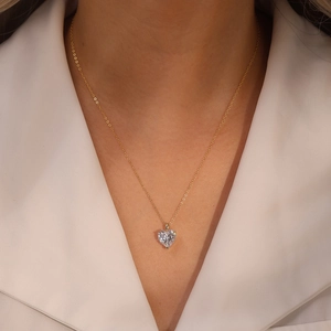 Vue détaillée du pendentif cœur en zircon sur chaîne dorée porté par un mannequin