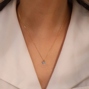Détail d'un collier avec pendentif en forme de cœur en or porté par un mannequin