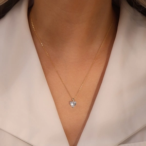 Gros plan d'un pendentif cœur en zircon avec chaîne dorée portée par une femme