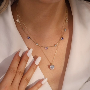 Détail d'un collier double rang en or avec zircons colorés en forme de cœur et pendentif