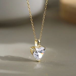 Gros plan du pendentif cœur doré en zircon avec serti à trois griffes sur chaîne fine