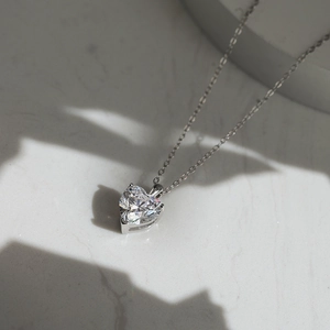 Détail du pendentif cœur en zircon avec chaîne en argent sur surface en pierre