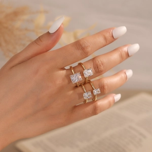 Detail of two gold-plated rings with rectangular zircon stones on model's fingers