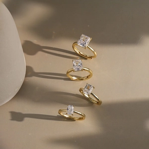 Set of four gold-plated wedding rings featuring emerald-cut cubic zirconia in sunlight