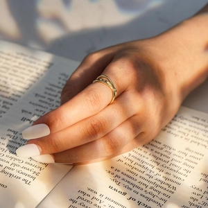 Minimalistischer goldener Mobius Wellenring an der Hand auf einem Buch im schicken Stil