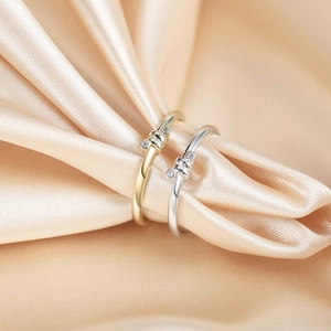 Detailed macro view of interlocking gold and silver knot rings on soft champagne silk fabric