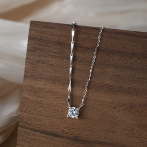 Detail of silver S925 necklace with zircon pendant on wood and silk background