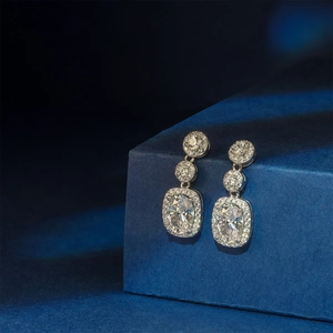 Elegant silver drop earrings with oval rhinestones on a textured blue gift box background