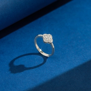 Elegant silver four-leaf clover ring with sparkling zircon pavé on blue background