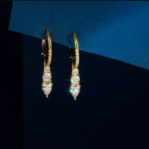 Detail of gold drop earrings with tiered round and pear-cut clear sparkling stones