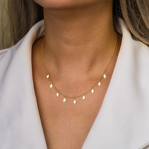 Minimalist gold necklace with diamond-shaped sequins on a female model with white suit