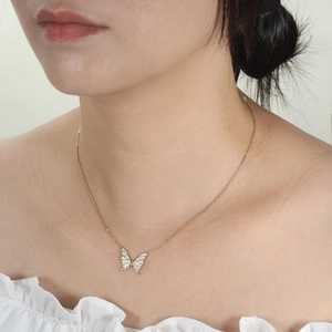 Elegant gold chain necklace with glowing blue butterfly pendant on female neck