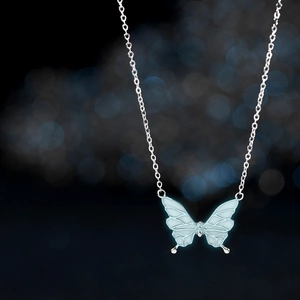 Macro shot of silver butterfly pendant with glowing blue wings and delicate chain