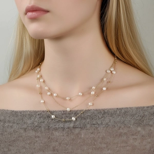 Collier triple rang en perles d'eau douce et chaînes dorées porté par un mannequin