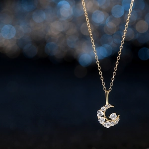 Elegant gold crescent moon necklace with heart-shaped zircon stones on starry blue background