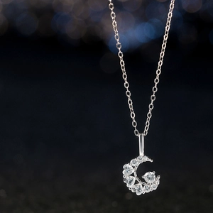 Macro shot of silver crescent moon necklace with inlaid heart-shaped zircon stones