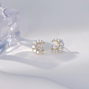 Exquisite gold crescent moon stud earrings with shimmering micro-pave crystals on white stand