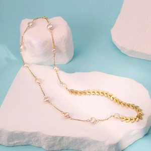 Minimalist freshwater pearl wheat ear necklace in gold finish on an elegant stone display
