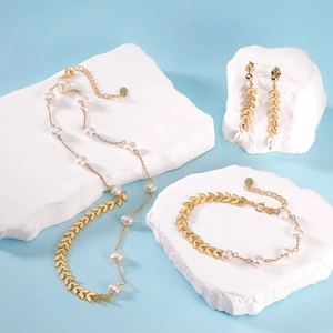 Elegant gold leaf pearl jewelry set with necklace bracelet and earrings on white stones
