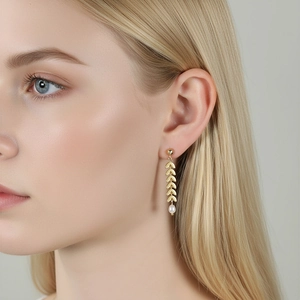 Elegant gold leaf-shaped drop earrings with white pearls shown on a female model